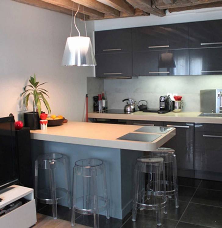 modele de cuisine semi ouverte grise avec ilot central et petit coin salle à manger, séparation en bois amovible, salon canapé violet et meuble tv blanc